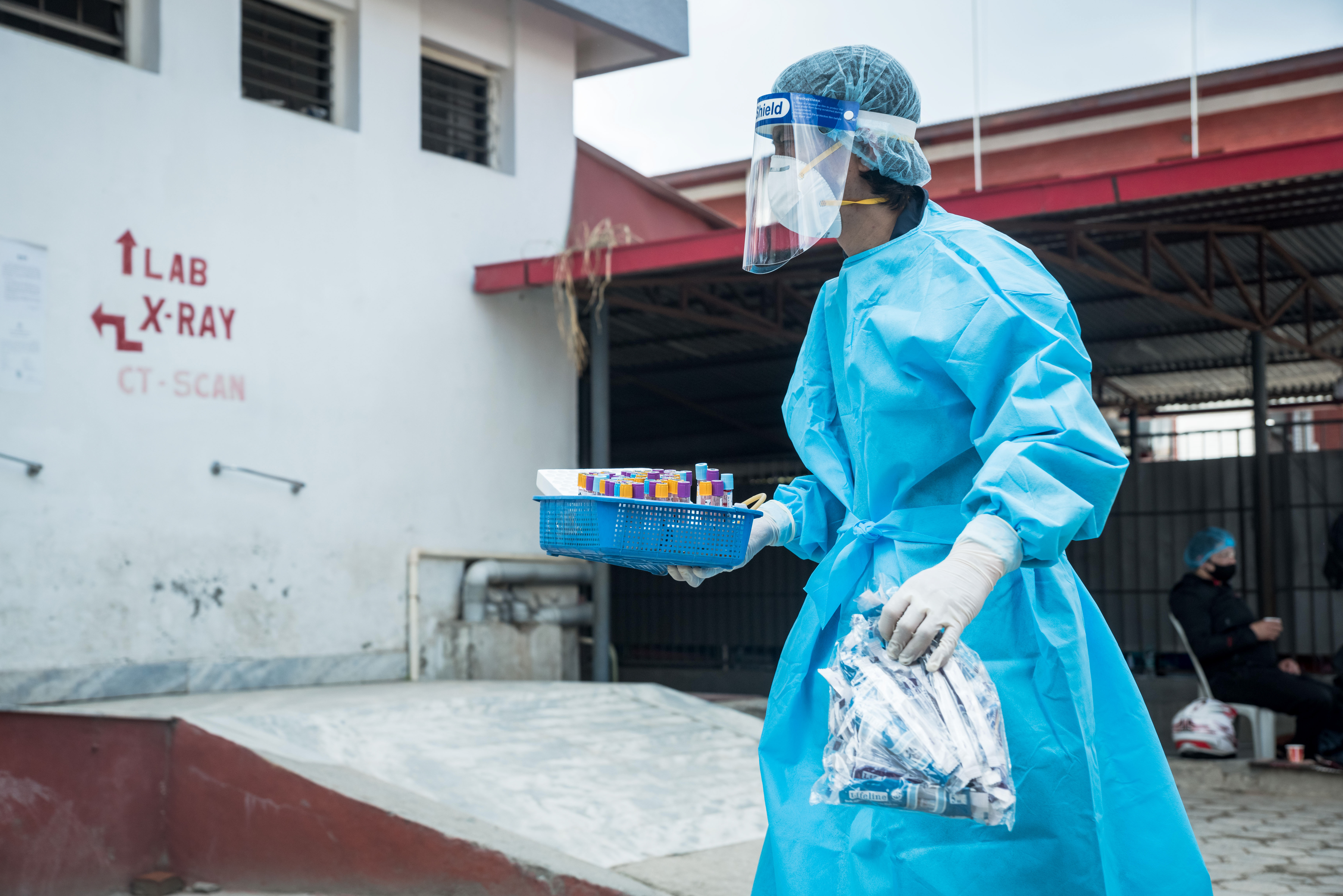 A health worker carries COVID-19 test samples to the laboratory in Sukraraj hospital, Teku, Nepal in 2021.